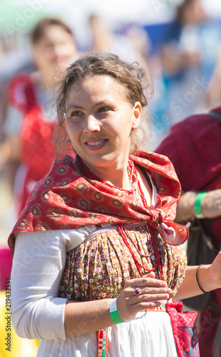 A woman in Russian folk clothes with a beautiful ornament, the sun is shining