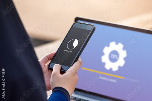 Hijab woman doing installing update on smartphone with installing upadate on screen laptop background