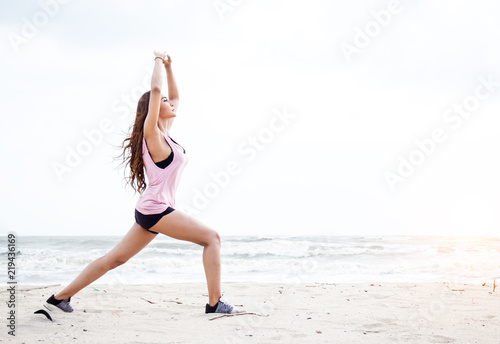 lThe beauty lady is exercise by raise her hands up in the air for stretch the muscles,on the beach,blurry light around. photo