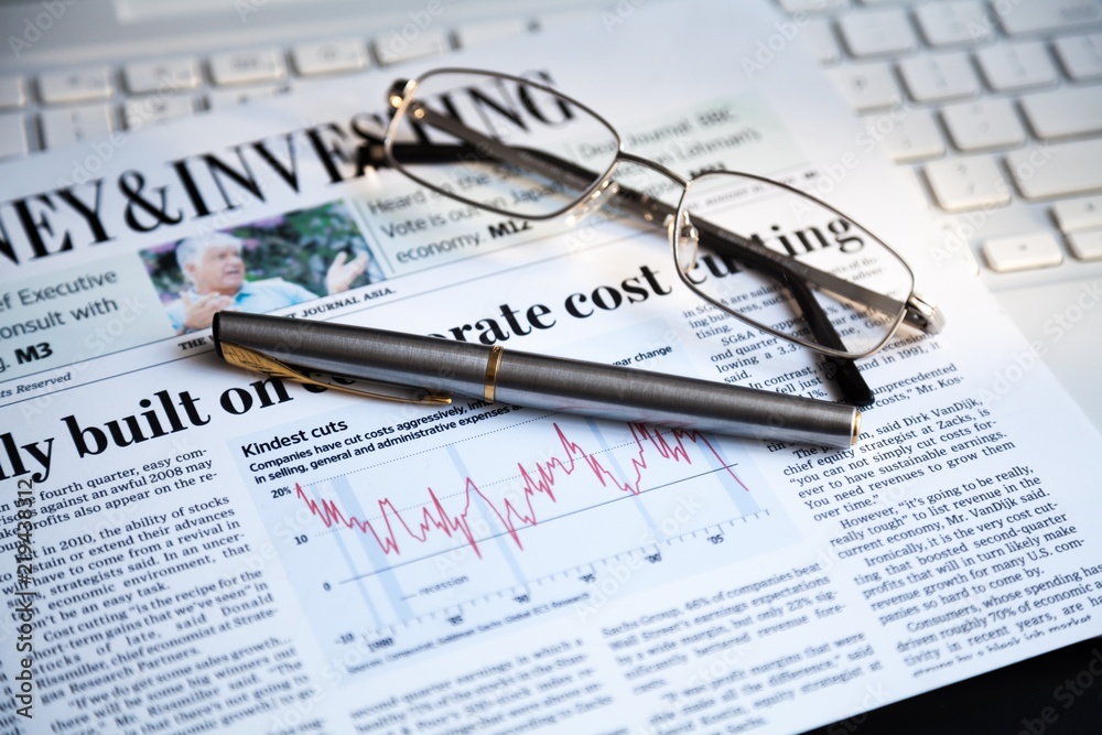 Glasses And Pen On Financial Newspaper And Laptop Close-up Glasses And Pen On Financial Newspaper And Laptop Close-up