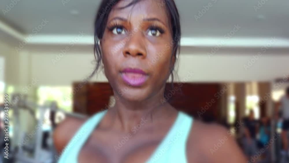 frontal close up head shot of young attractive and fit black afro American woman running hard on treadmill workout sweaty and determined at fitness club in exercise and healthy lifestyle frontal close up head shot of young attractive and fit black afro American woman running hard on treadmill workout sweaty and determined at fitness club in exercise and healthy lifestyle