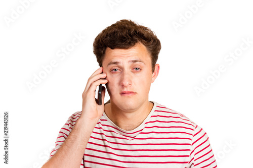 A crying man reads a text message on his phone. Sms with bad news. emotional man isolated on white background