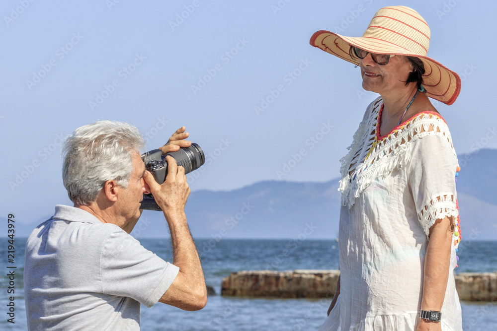 Senior man photographing his wife with modern camera