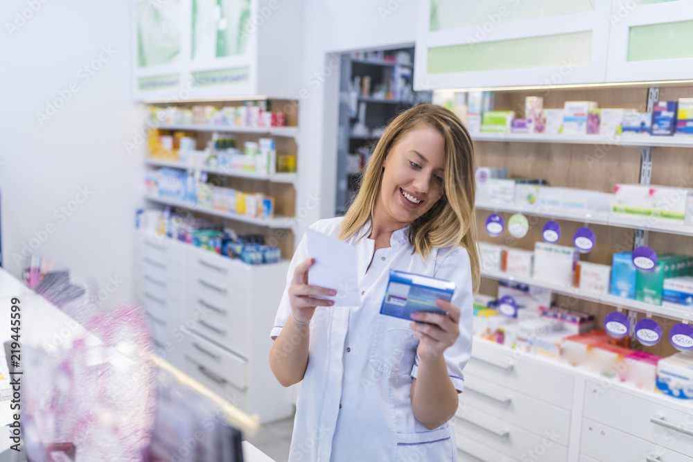 Beautiful smiling female pharmacist working in a pharmacy (or drugstore) with customer friendly attitude