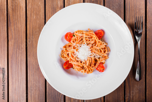Pasta Spaghetti with olive oil, cheese, herbs and tomatoes on wooden background, Italian cuisine. Ingredients on table