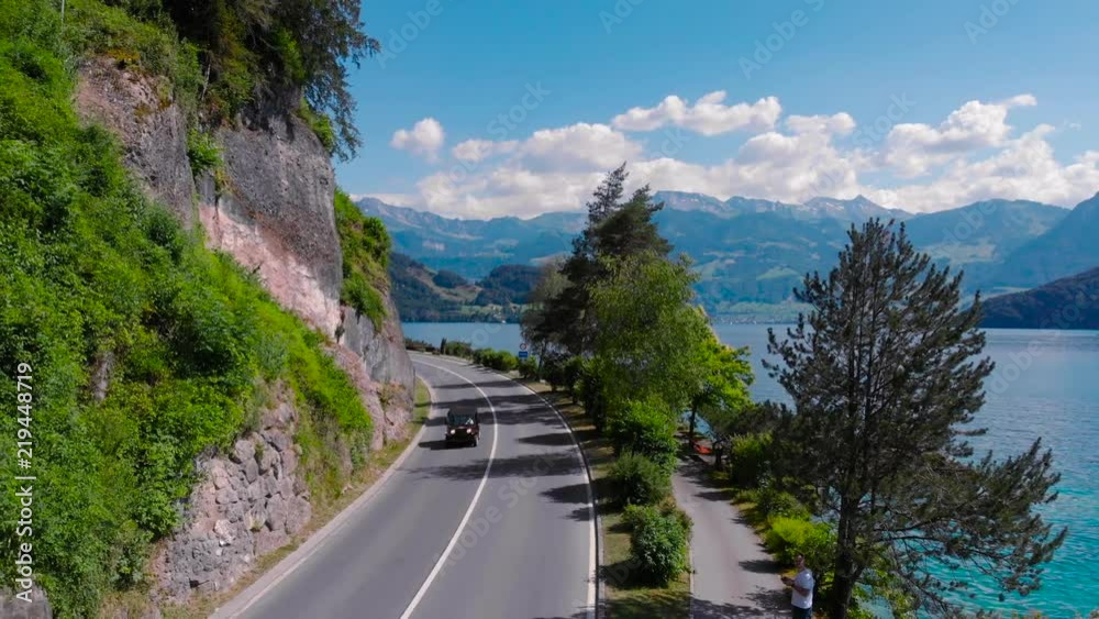 Amazing aerial view of alpine road and lake, Switzerland, Europe. Footage. Car driving motion on a highway road at Lake. summer road trip, vacation concept Amazing aerial view of alpine road and lake, Switzerland, Europe. Footage. Car driving motion on a highway road at Lake. summer road trip, vacation concept