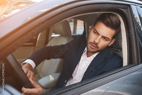 Businessman in car. Rear view of young handsome man looking on the right while driving a car © Friends Stock