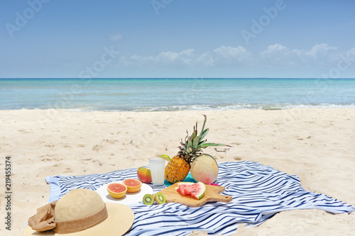 Beach picnic with lemonade and fruits (pineapple, grapefruit, kiwi, watermlon, cantaloupe, mango) photo