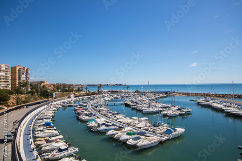Small marina with yachts and fishing boats in the Mediterranean Sea. Yachting port with buildings in the background on a summer day
