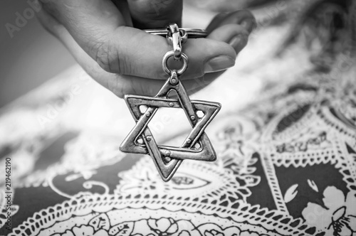 Young woman's hand holding a Star of David - Magen David key chain. The State of Israel, Holocaust remembrance, Judaism, Zionism concept image. Black and white image. photo