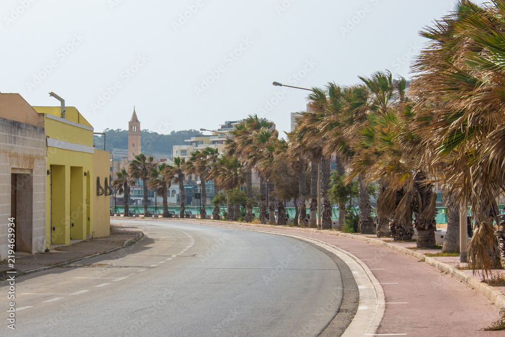 An empty road in a small Marsascala (Malta) village on a windy day with Sant Anna's church in the background