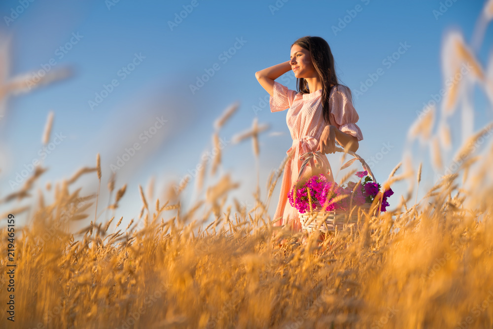 Obraz premium Woman in wheat field at sunset