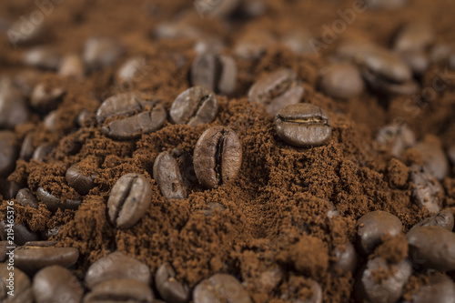 Macro of a coffee bean in roasted coffee grounds.