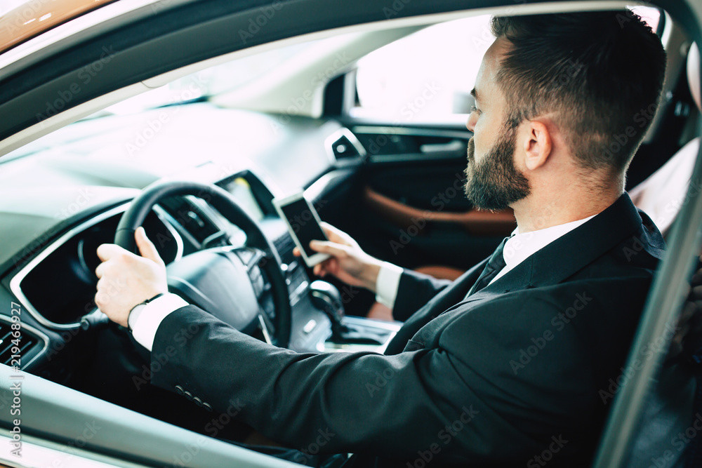 Back cropped photo of young businessman using smart phone in car Back cropped photo of young businessman using smart phone in car