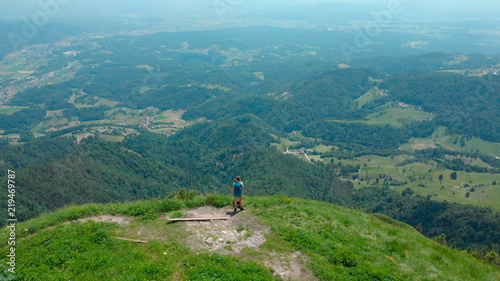 AERIAL: Unrecognizable female hiker looking at the picturesque green landscape