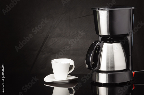 Coffee machine with pot and cup on the black mirror background