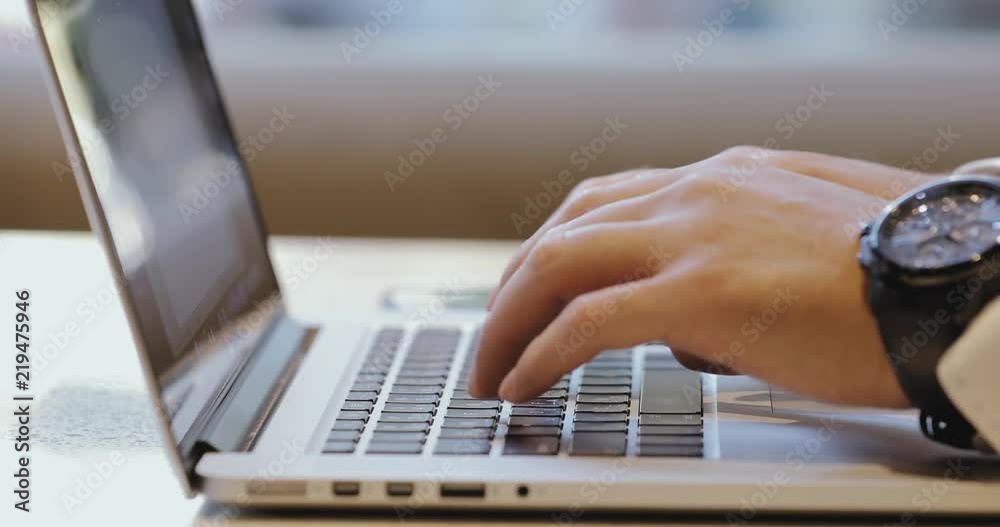 Male hands typing text on keyboard, freelancer working by laptop computer in cafe