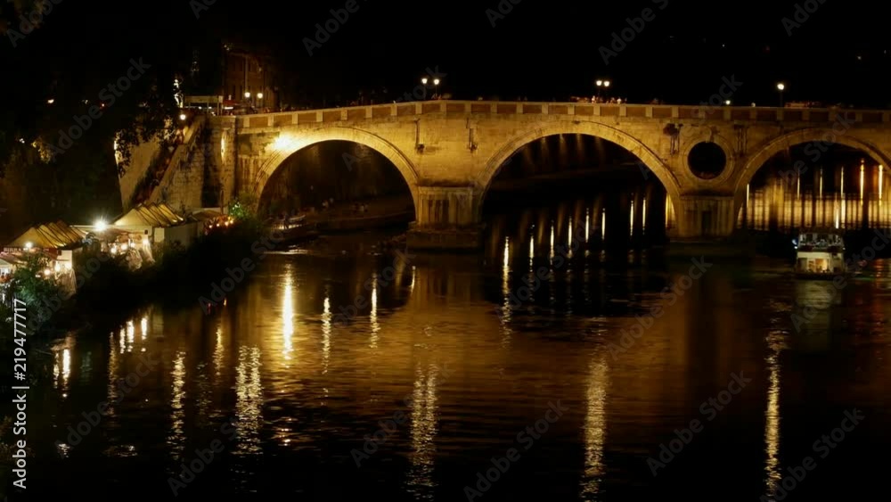 Timelapse Rome by night at Summer - Many people walk on the illuminated quays near the river with the Sisto bridge and the dome of St. Peter in the distance Timelapse Rome by night at Summer - Many people walk on the illuminated quays near the river with the Sisto bridge and the dome of St. Peter in the distance