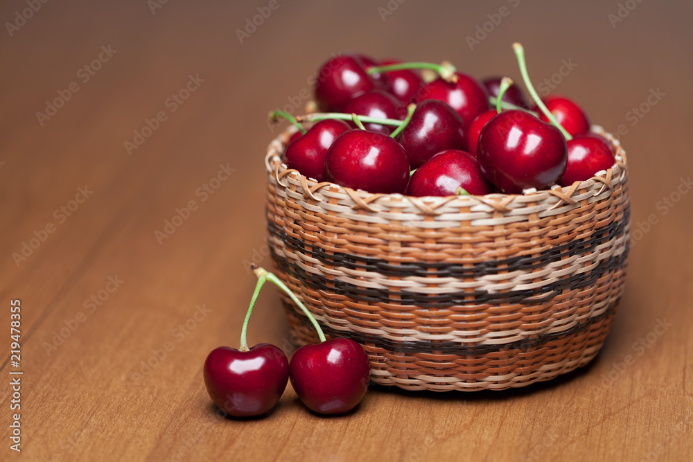 Red Ripe Cherries in a basket on a wood table Red Ripe Cherries in a basket on a wood table