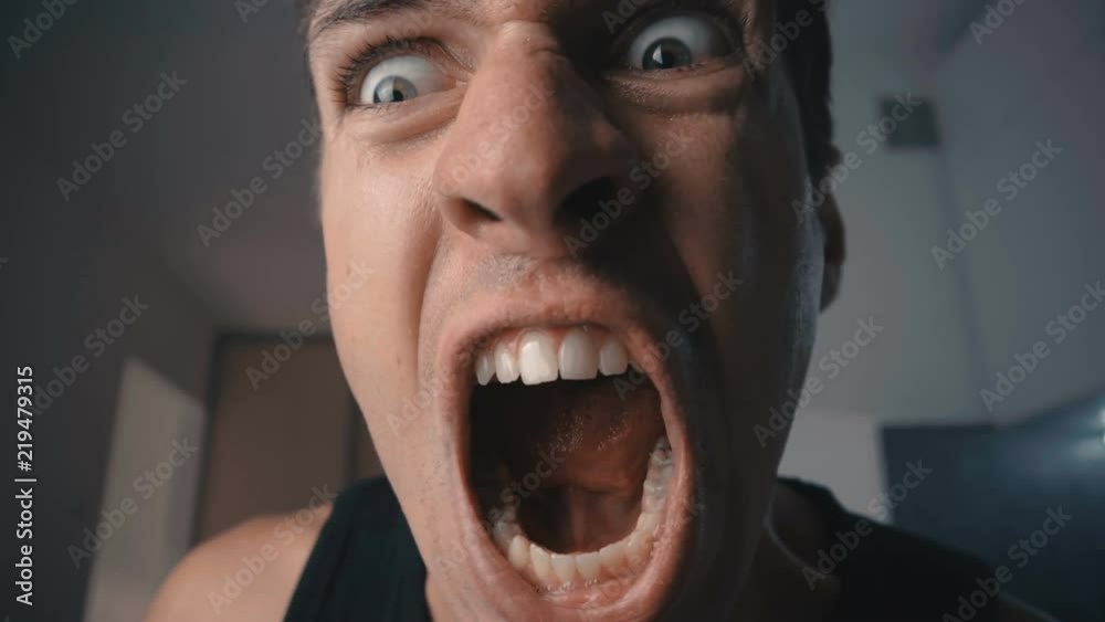 Angry man screaming and threatening with violence at home in the kitchen.