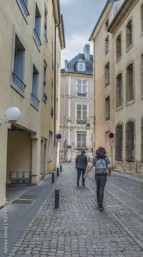 Two men walking down historic, narrow, cobbled street in Northern France Two men walking down historic, narrow, cobbled street in Northern France