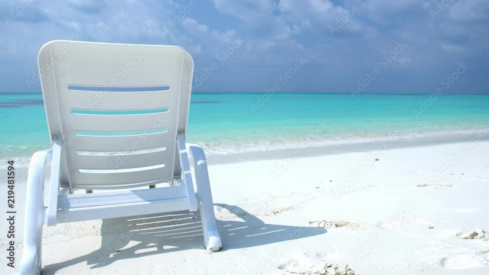 One sunbed on tropical calm shore with turquoise sea water and white sand One sunbed on tropical calm shore with turquoise sea water and white sand