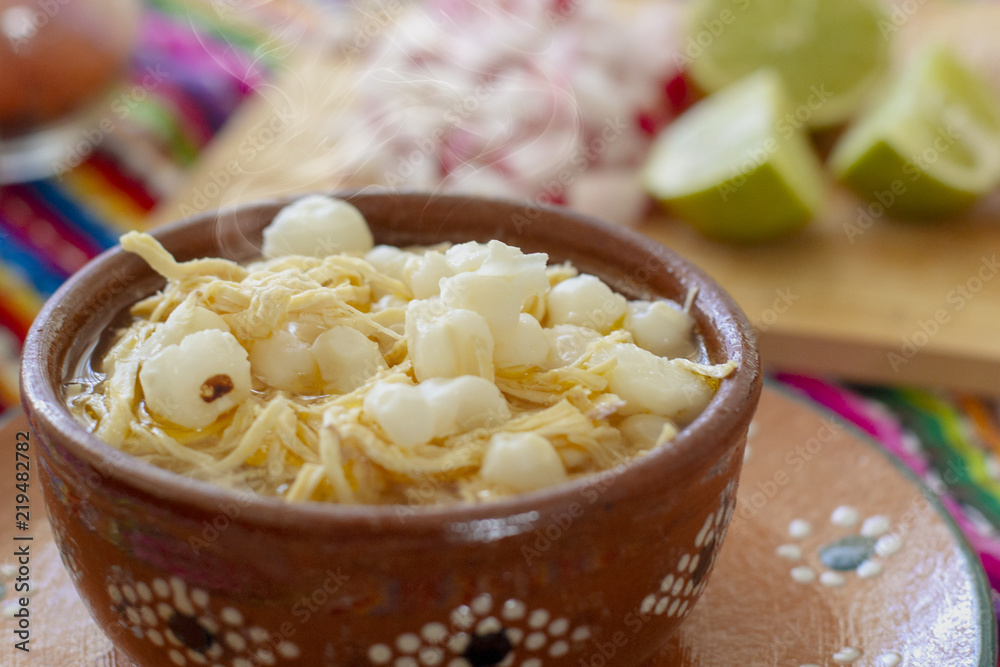 Foto de Pozole blanco con pollo, acompañado con rábanos, limones y tostadas  en fondo de colores mexicanos do Stock | Adobe Stock