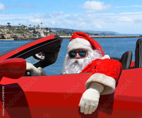Santa Claus sitting in his red sports car at the beach © Steve Cukrov
