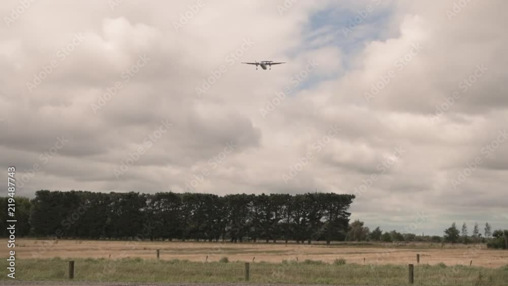 Low angle, plane flies over rural field in slow motion