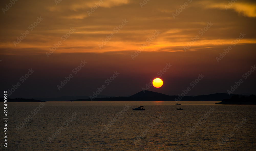Romantic sunset over sea with boats in distance