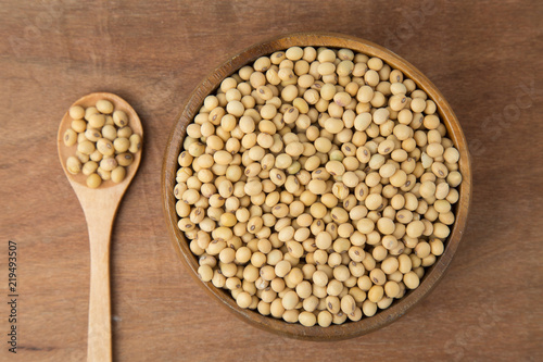 Soybeans in wooden bowl and spoon on wooden background.