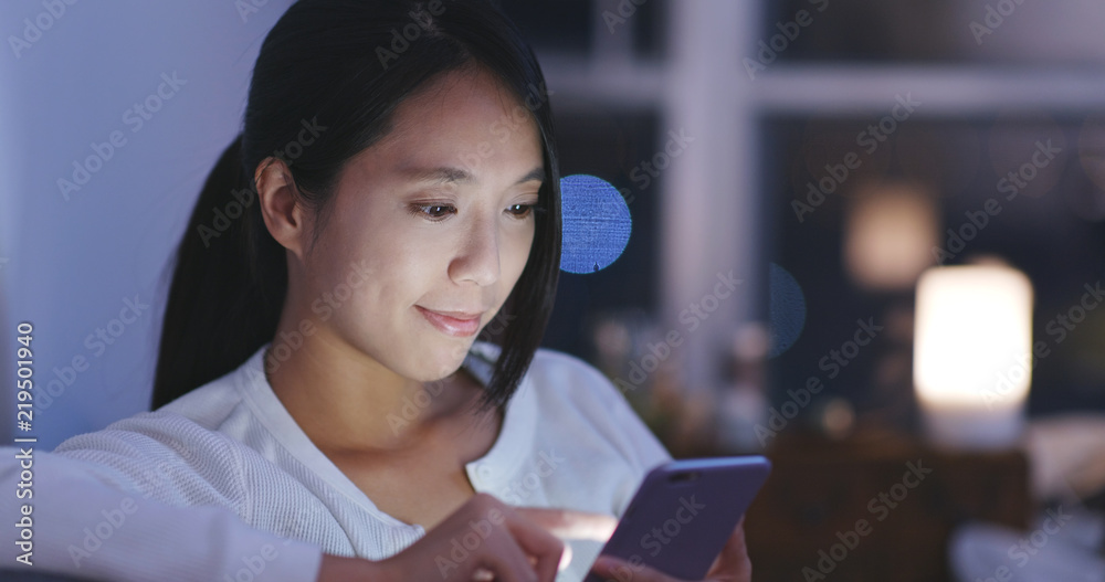 Naklejka premium Woman looking at mobile phone at night