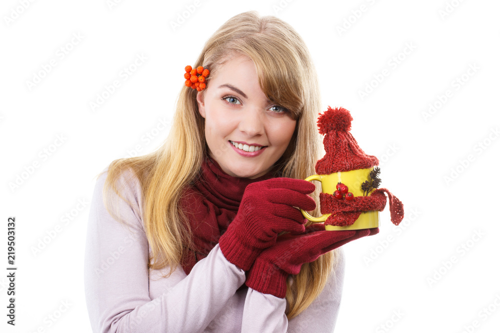 Smiling girl in gloves holding cup of tea with woolen scarf and cap