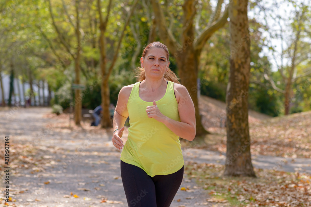 Determined middle-aged woman jogging in the park