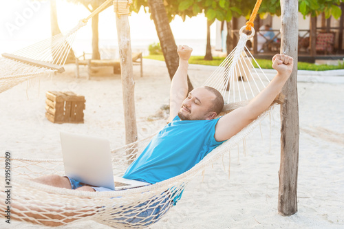 The man quite stretches lying in a hammock with a laptop. The concept of remote work