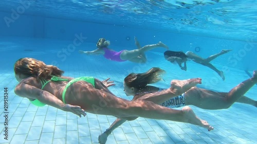 People dive under blue water snorkeling in pool , slow motion