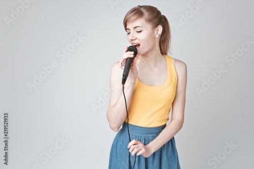 Beautiful young woman singing into a microphone karaoke showing expressions and feelings © olarty
