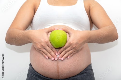 close up of Pregnant woman with fresh green apple.Pregnancy, healthcare, food and happiness concept.Healthy pregnancy. photo