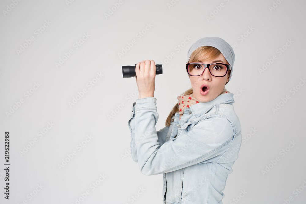Young hipster surprised woman with binoculars in winter hat and glasses Young hipster surprised woman with binoculars in winter hat and glasses
