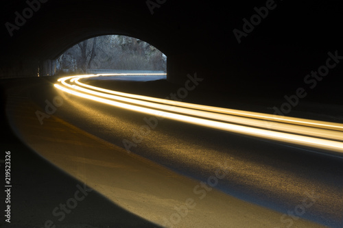 Abstract rays of white and yellow light with a car tunnel as background