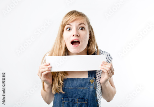 Attractive woman holding paper blank in her hands. Portrait of emotional young woman showing surprised and happy emotions