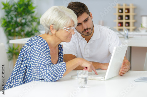 young man helping senior lady to use laptop