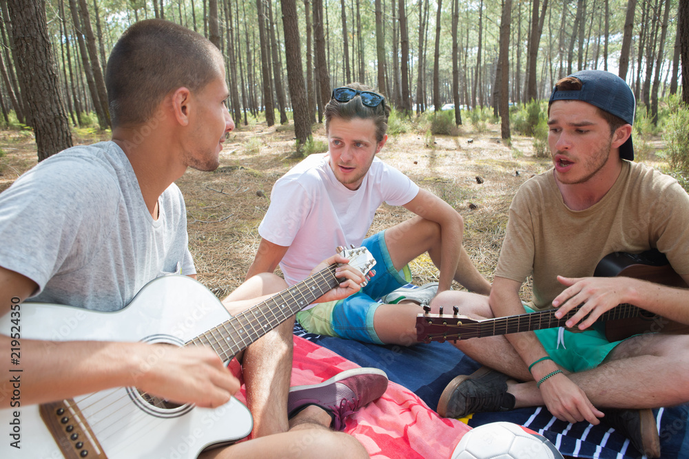 friends playing the guitar on the beach