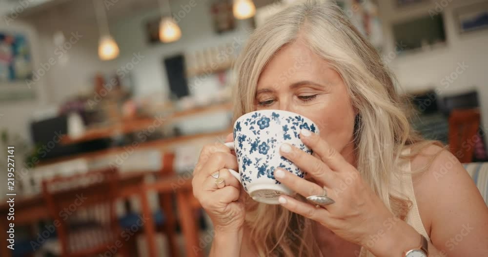 Portrait of beautiful smiling mature woman drinking coffee at cafe
