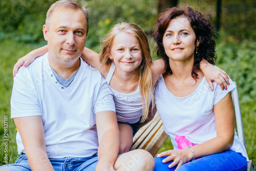 Portrait of joyful family with child. Father, mother and daughter having fun outdoors in garden, playing together in summer park. © Iryna