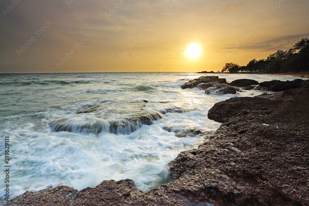 Sea waves lash line impact rock on the beach with beautiful sunset time, Eastern of Thailand