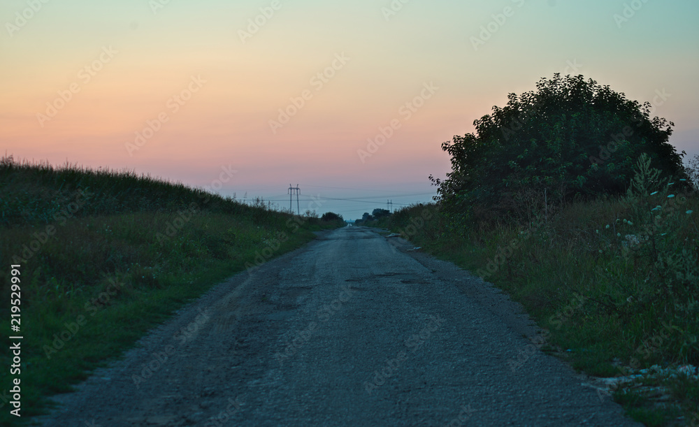 Sunset over empty countryside road, summer landscape