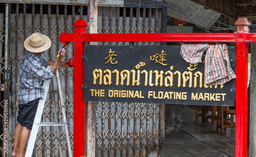 Fotografie Man painting sign The original floating market, sign written in chinese, thai
