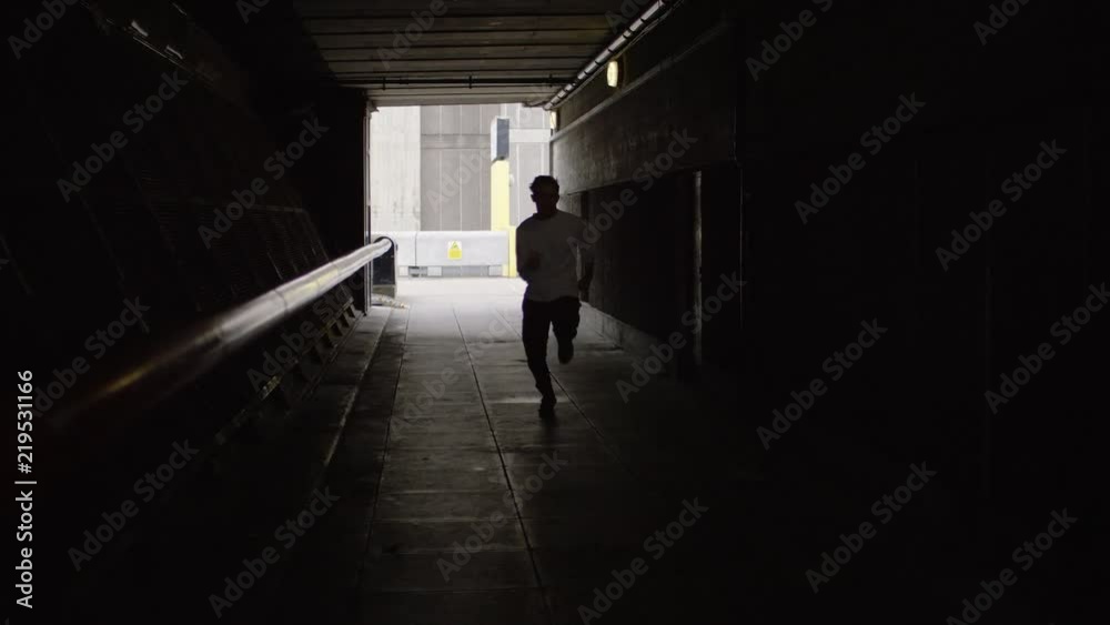 Man running in a tunnel speeds past the camera, in slow motion