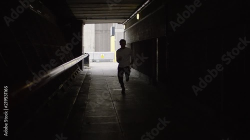 Man running in a tunnel speeds past the camera, in slow motion photo